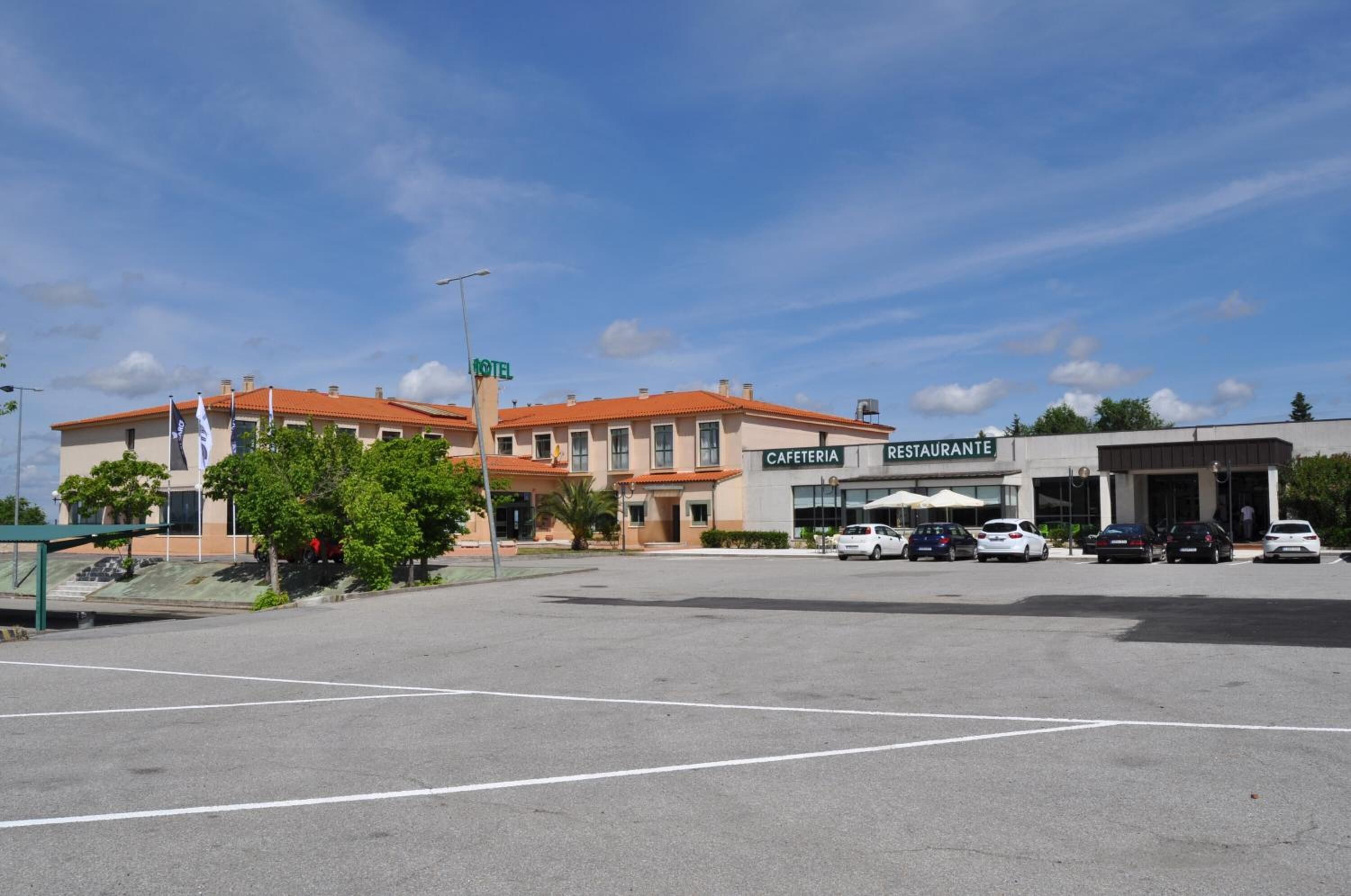 A hotel with a sign indicating a restaurant and cafeteria. There are cars parked in front.