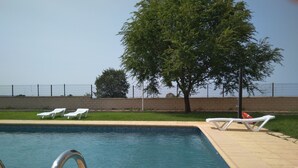Una piscina con sillas de descanso blancas y un flotador.