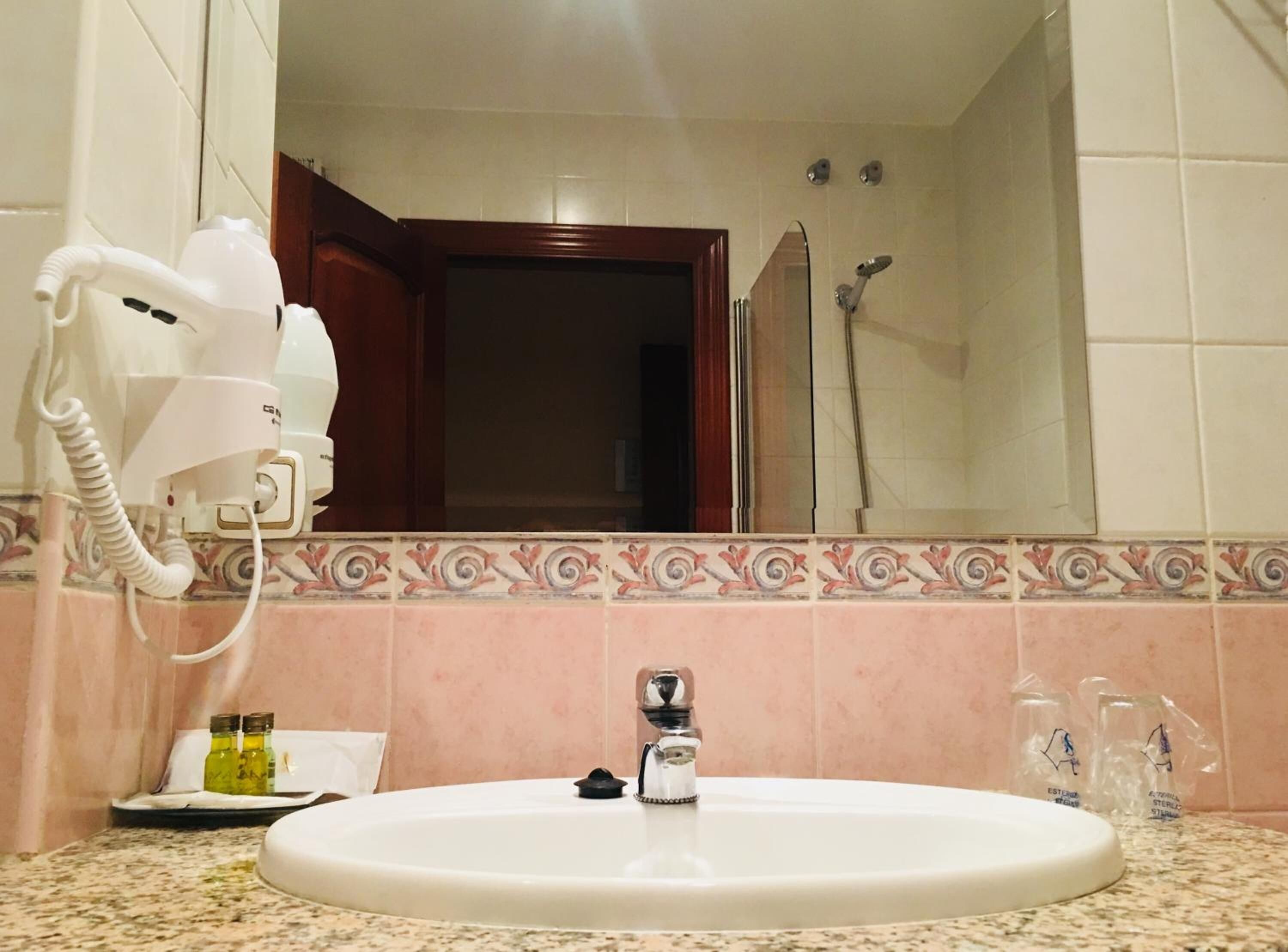 Baño con lavamanos, secador de pelo y artículos de aseo.