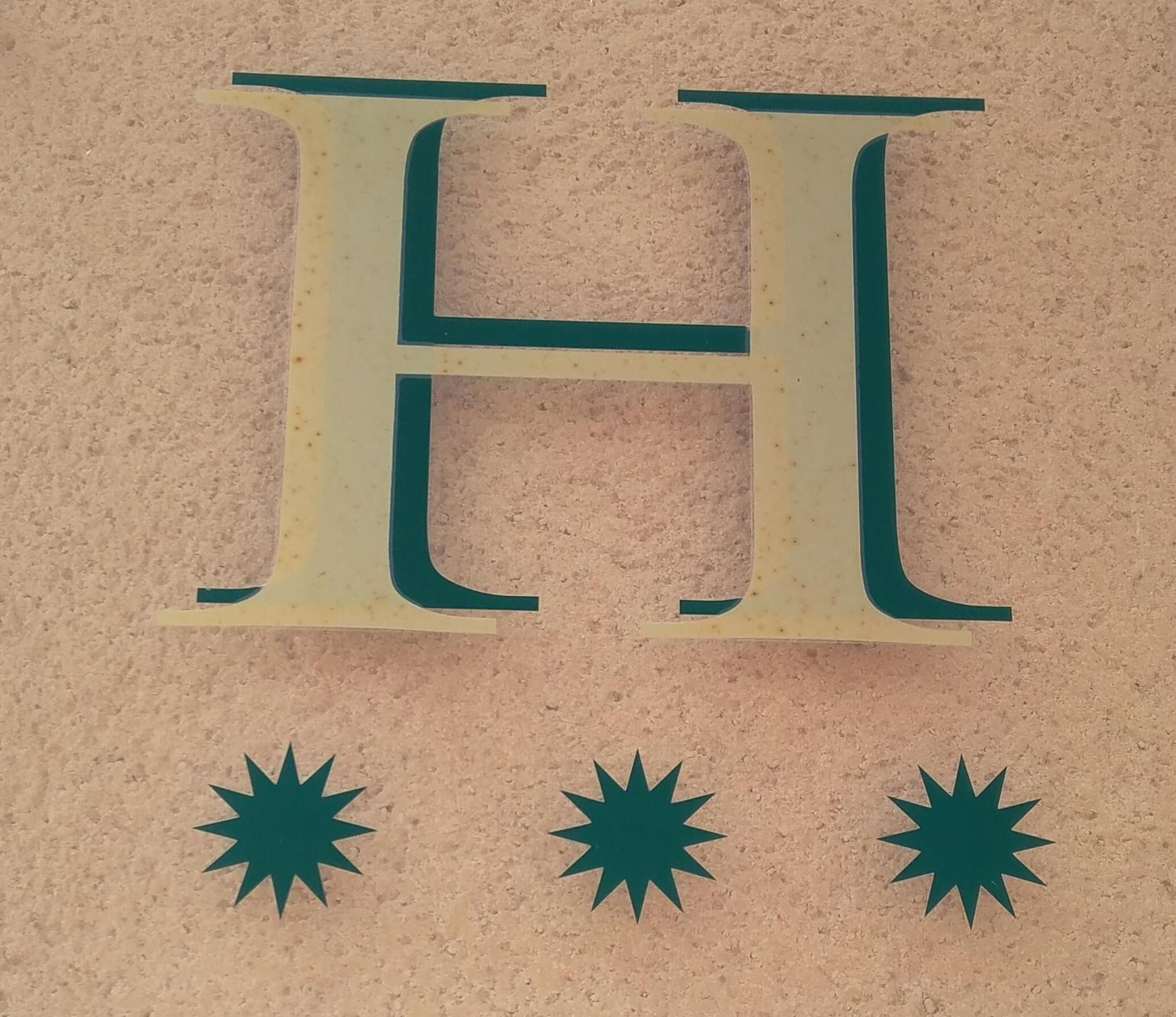 Una letra H mayúscula y prominente con tres figuras similares a estrellas debajo.