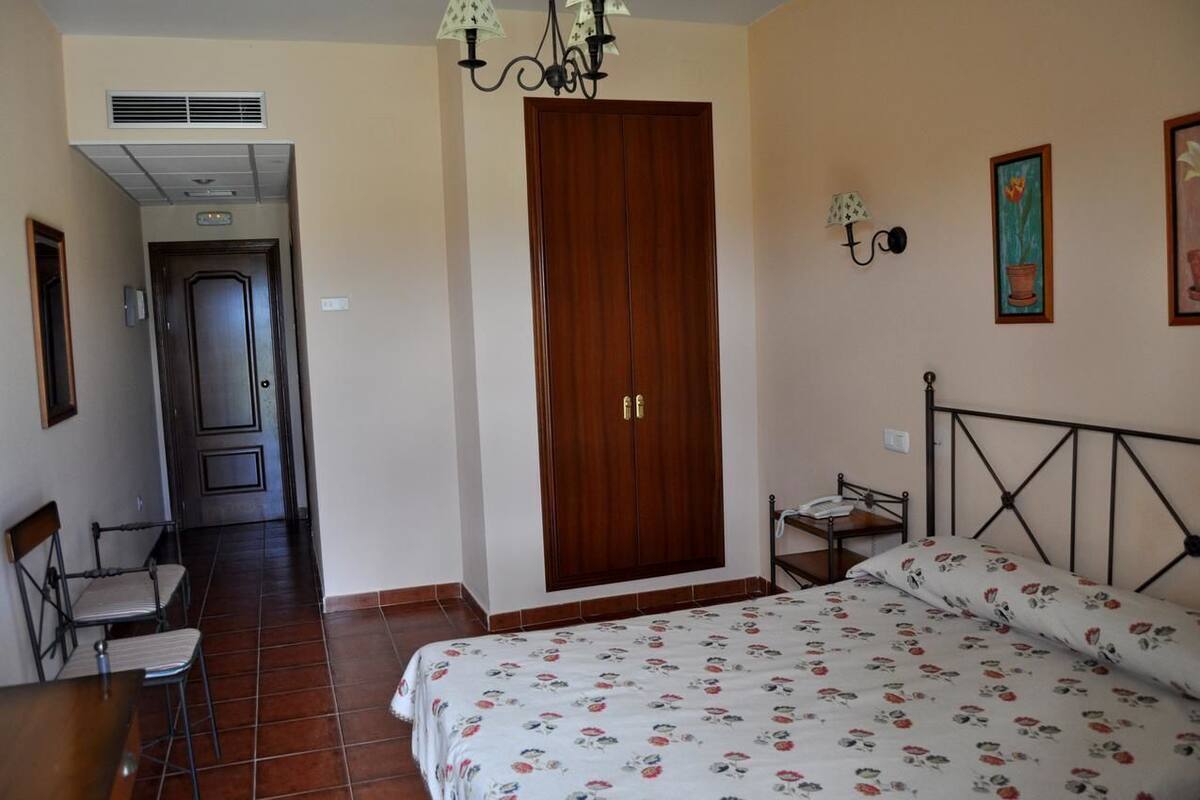 Ein Schlafzimmer mit Bett, Kleiderschrank, Stuhl, Tisch und Lampe.