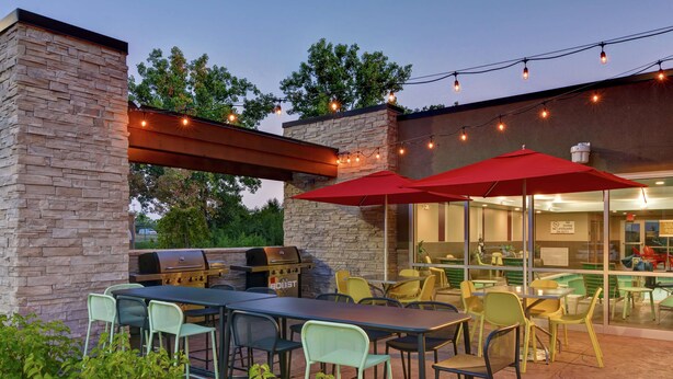 An outdoor patio with stone walls, a grill, and string lights.