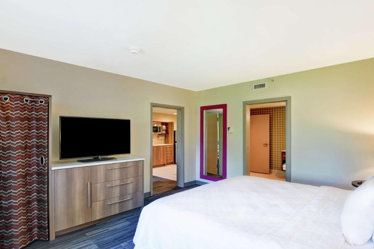 A hotel room with a bed, a TV, a wardrobe, and a bathroom door.