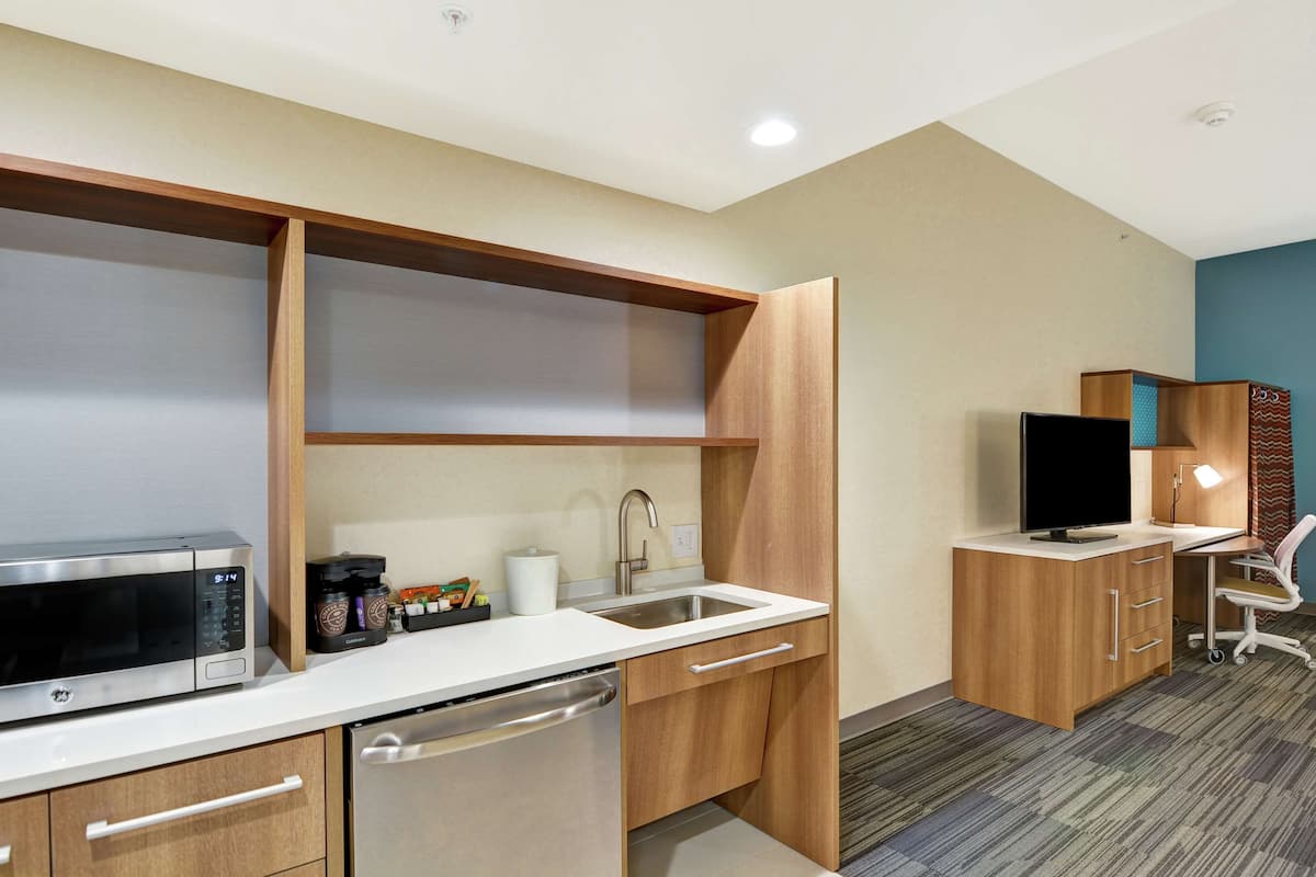 A compact kitchenette with a microwave, coffee maker, and sink.