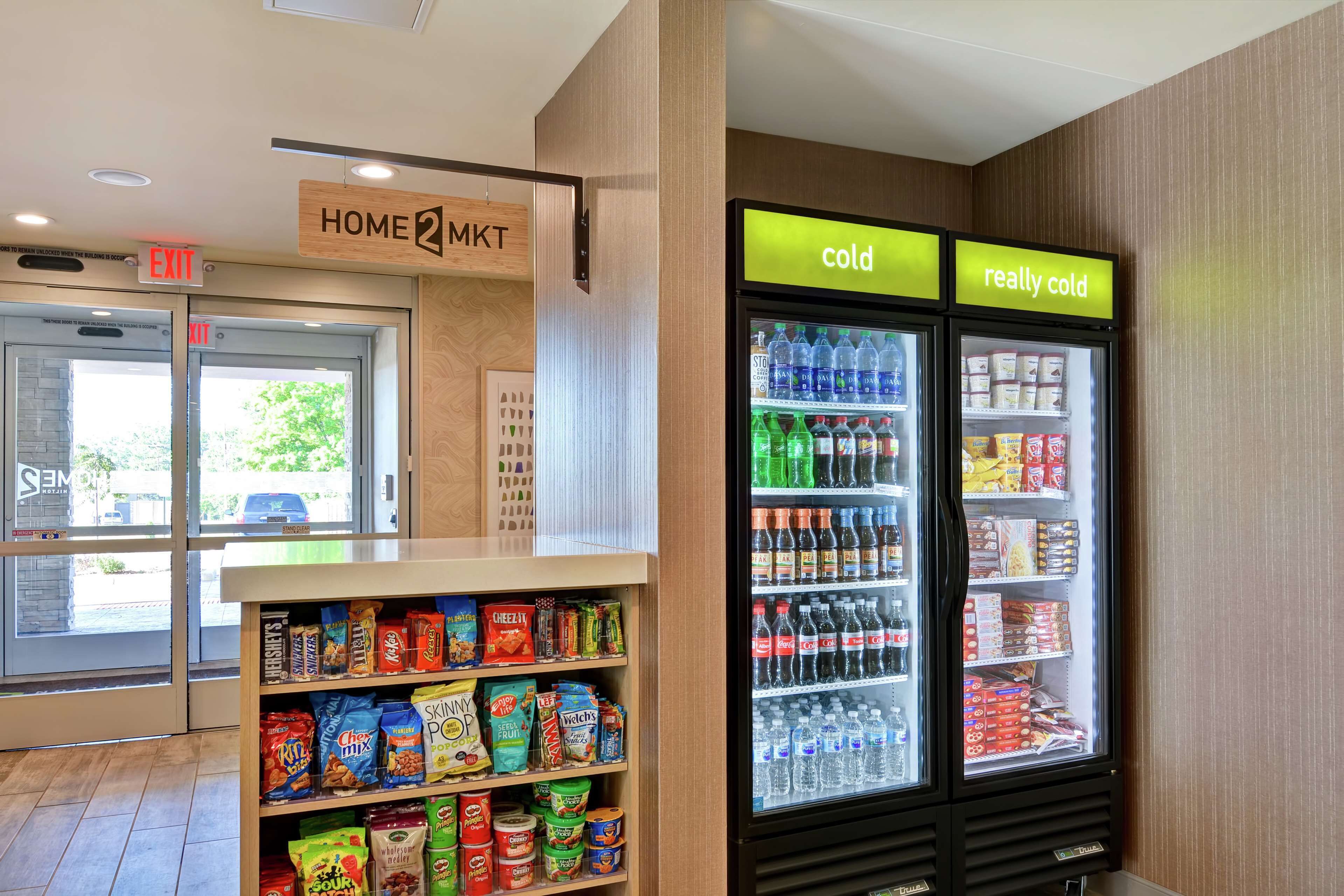 A snack area with shelves of chips and snacks, a freezer with 'cold' and 'really cold' sections, and an exit sign.