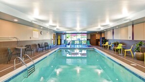 A swimming pool with a tiled deck, lounge chairs, and a sunshade area.