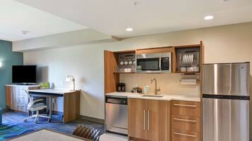 A modern kitchen with stainless steel appliances, wooden cabinets, and a dining area with a table and chairs.