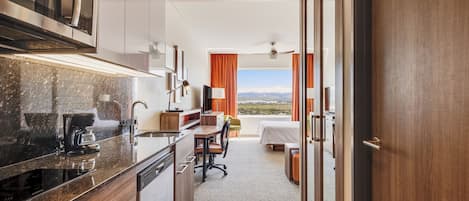 Una habitación de hotel moderna con cocina, una mesa de comedor y una cama.