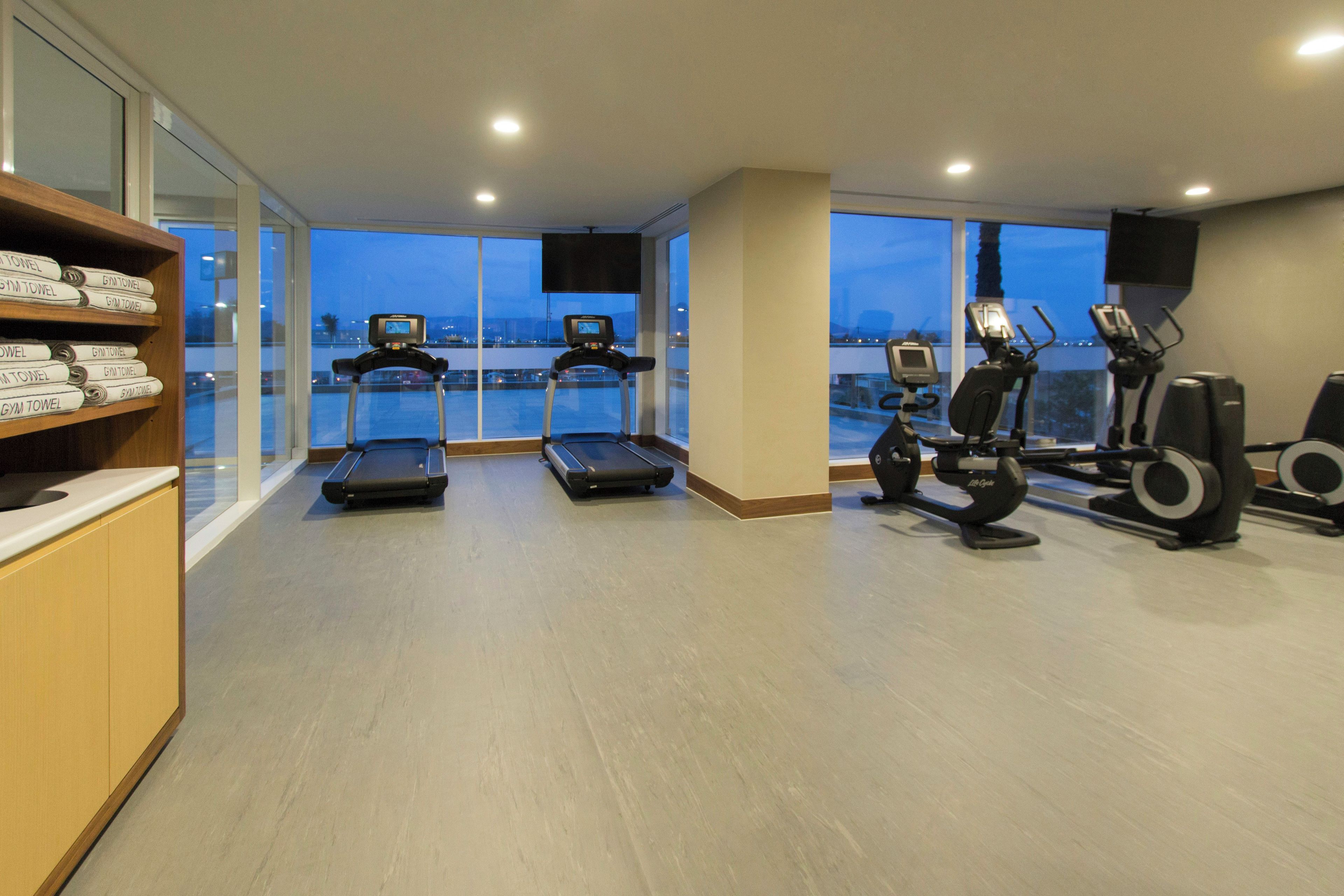 A gym with treadmills, stationary bikes, and a wall of gym towels.