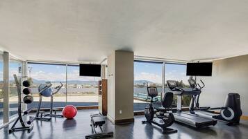 A gym with exercise equipment, large windows, and a view of the outdoors.