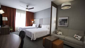 Habitación de hotel con dos camas, un sofá, un escritorio y un ventilador de techo.