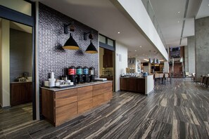 A modern kitchen with a herringbone-patterned backsplash, wooden cabinetry, and a central island with bar stools.
