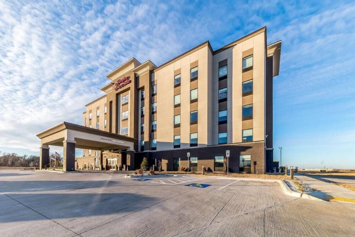 A modern hotel with a covered entrance, multiple floors, and a parking lot.
