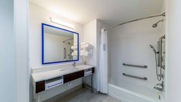 Un baño moderno con lavamanos, espejo y ducha blancos.