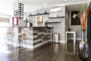 Een moderne keuken met een bar, houten krukken en een grote vaas.
