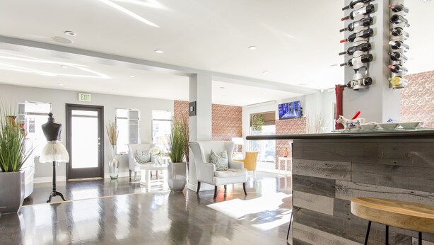 Eine moderne Lobby mit poliertem Boden, einem Empfangstresen und einem wandmontierten Weinkühlschrank.