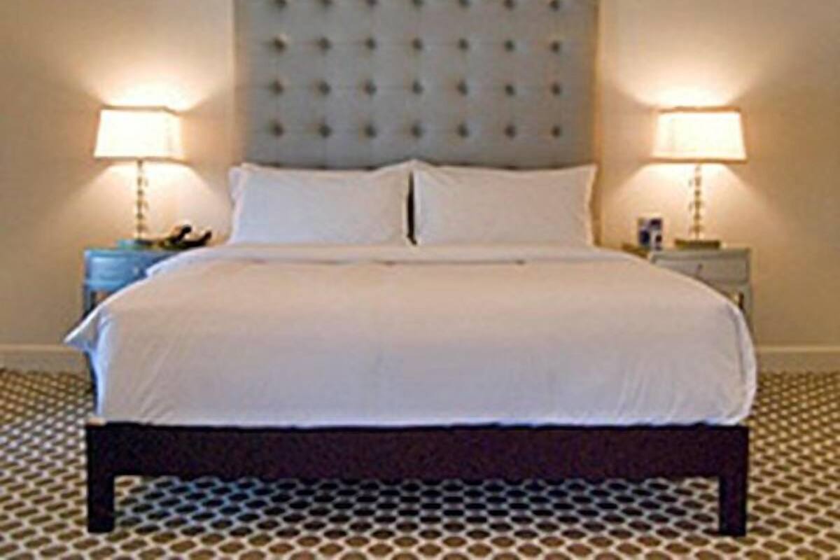 A neatly made bed with a tufted headboard, two bedside tables with lamps, and a patterned carpet.