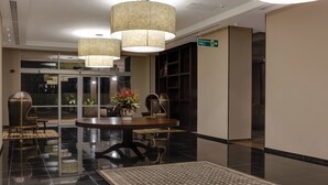 A lobby with a round table, chairs, a large rug, and a hanging lamp. - Protea Hotel Owerri Select (Owerri)
