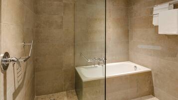 Un baño moderno con cabina de ducha de vidrio, bañera y un perchero para toallas.