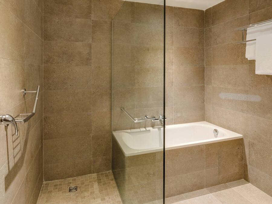 Un baño moderno con cabina de ducha de vidrio, bañera y un perchero para toallas.