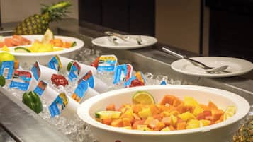 A buffet with various fruits and vegetables on ice, including pineapple, melon, and bell peppers.