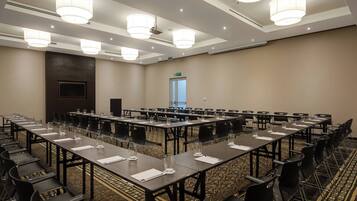 A conference room with long tables, chairs, and a television screen.