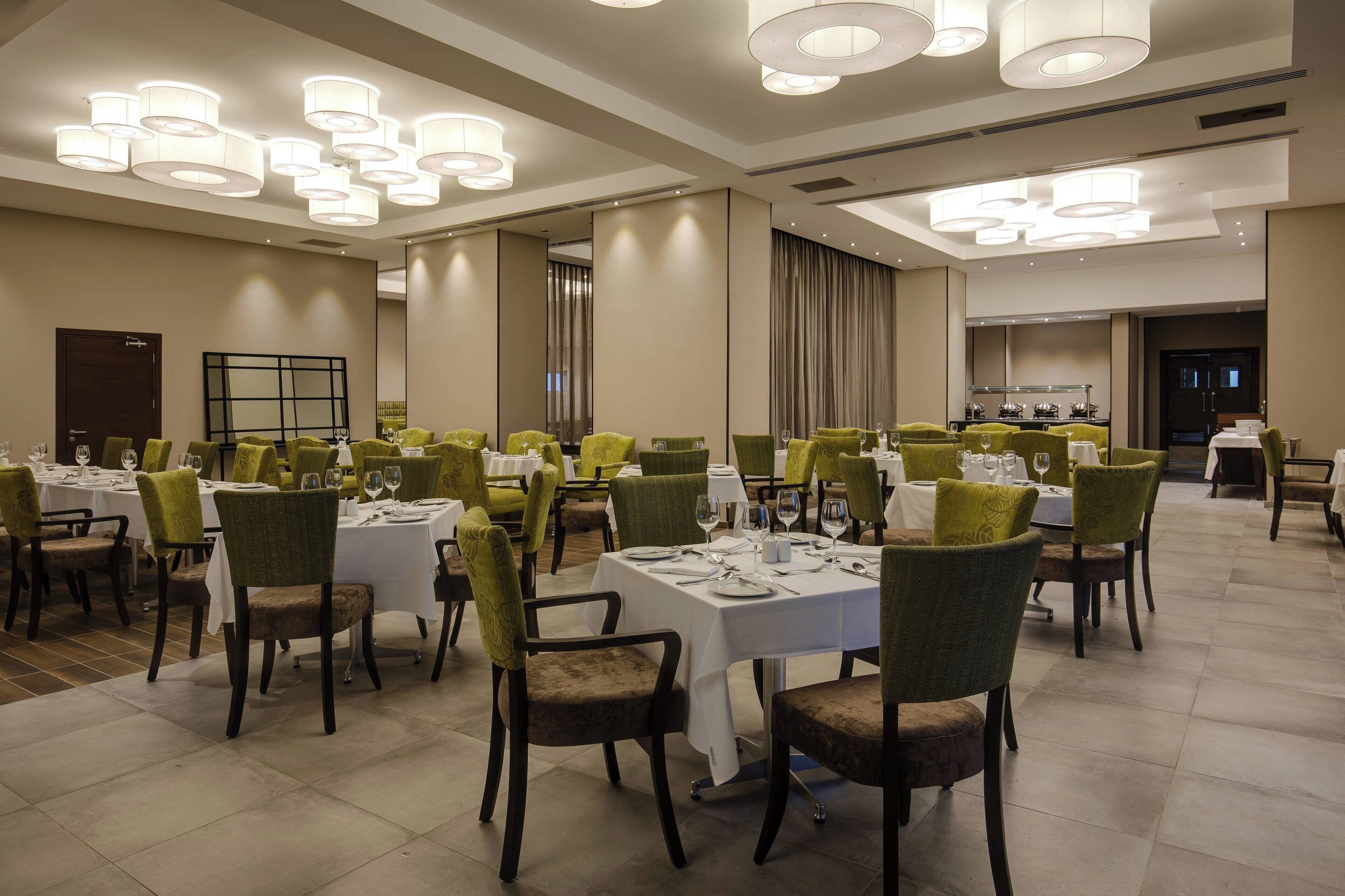 Un comedor con varias mesas dispuestas para comensales, cada una con sillas y vajilla.