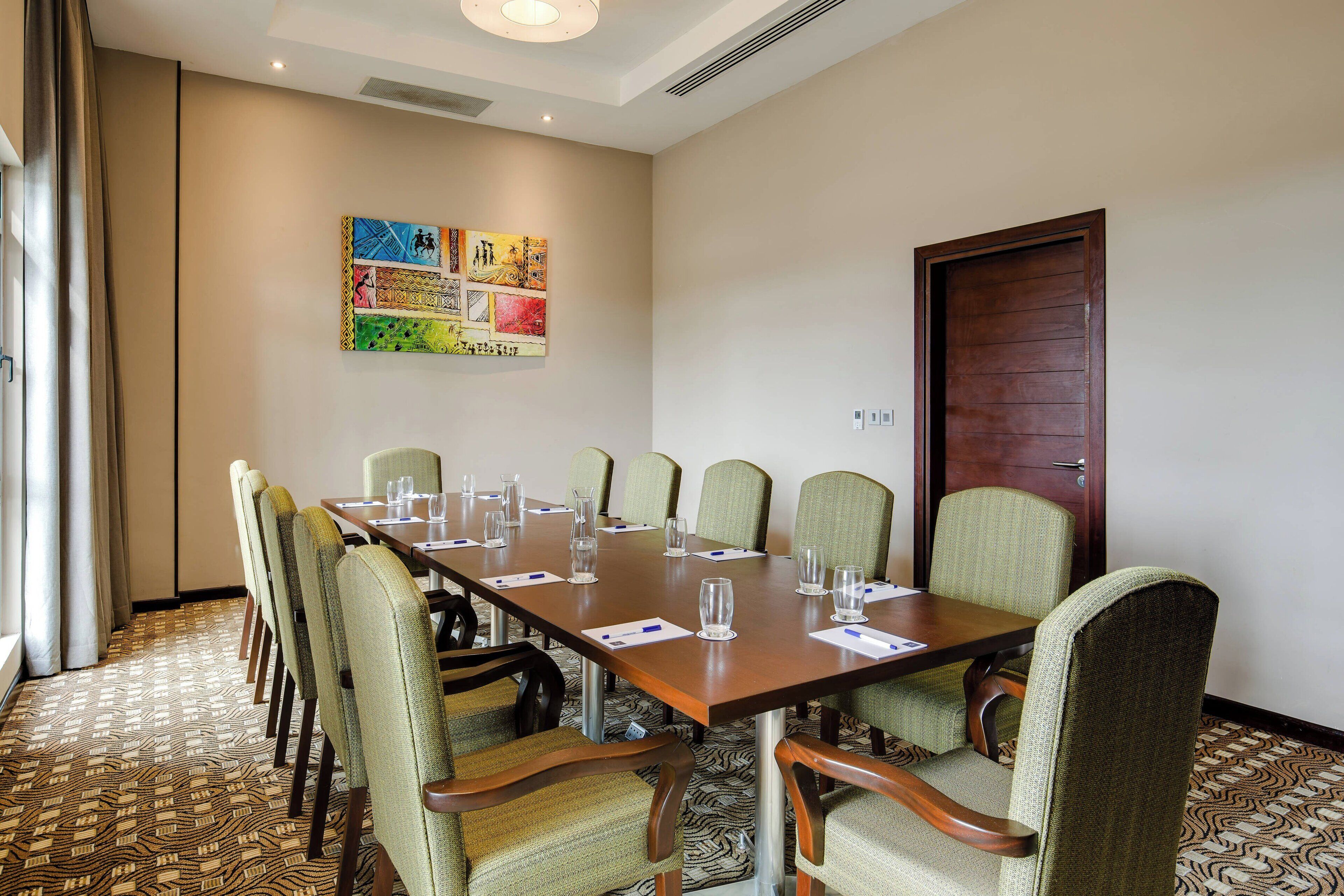 A conference room with a long table, chairs, and a door.