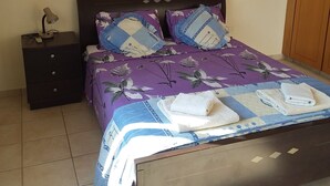 Un dormitorio con una cama, una mesita de noche, un aire acondicionado y un armario de madera.
