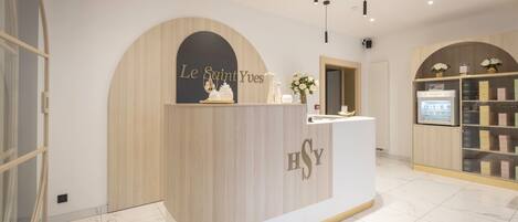 A reception area with a curved counter, a sign reading "Le Saint Yves", and a refrigerator with a display.