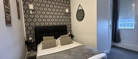 A neatly made bed with a grey blanket, a headboard, and two bedside lamps.