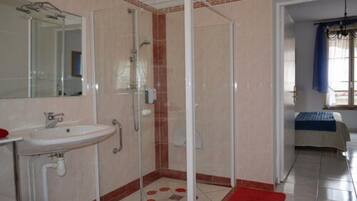 Une salle de bain avec une douche à parois de verre, un lavabo et un miroir.