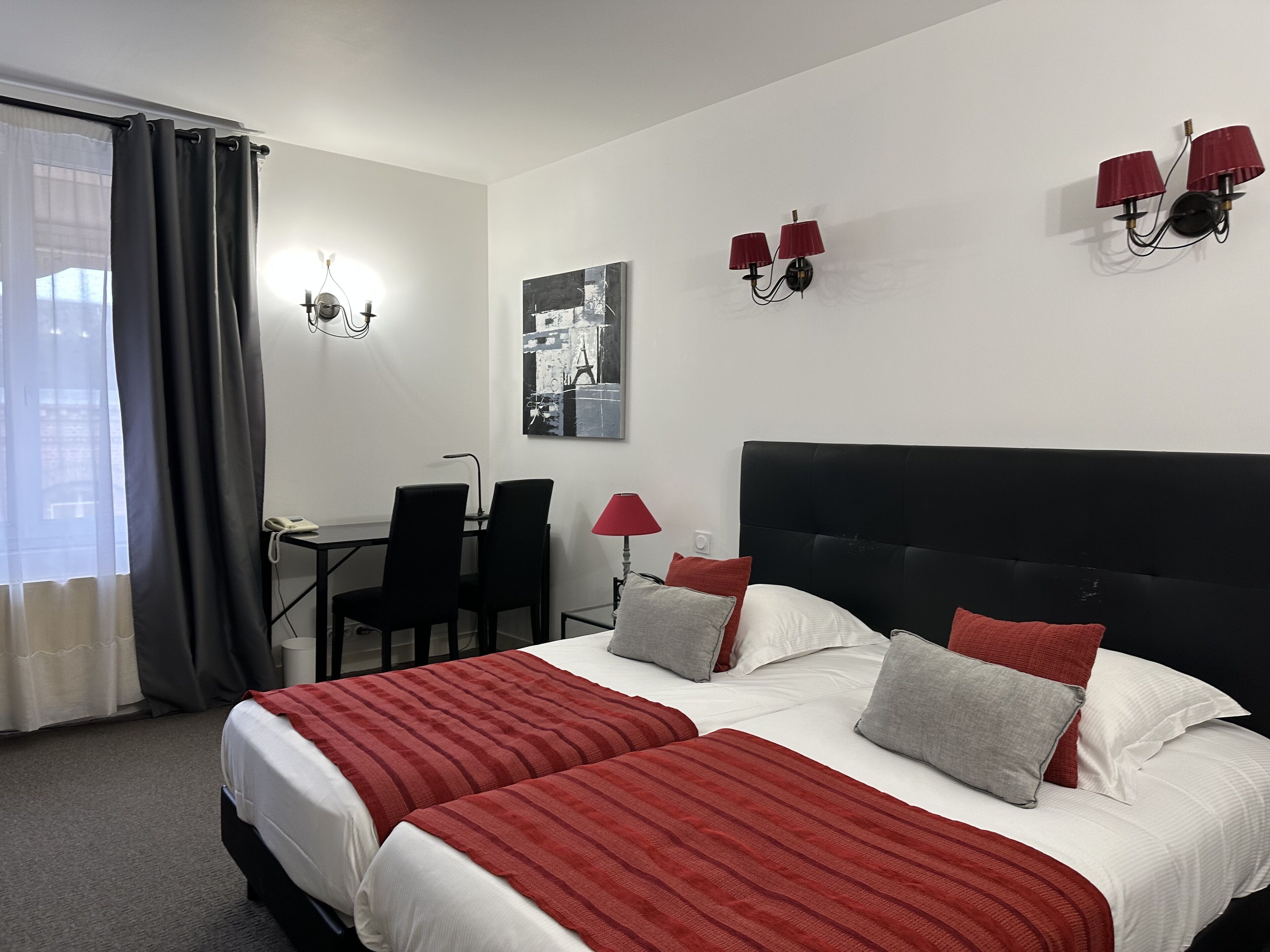 Una habitación de hotel con cama, dos sillas, un escritorio y una lámpara.