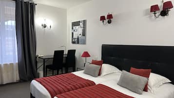 A hotel room with a bed, two chairs, a desk, and a lamp.