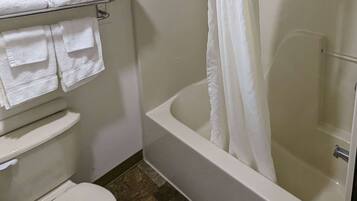 A bathroom with a bathtub, toilet, and a towel rack with folded towels.