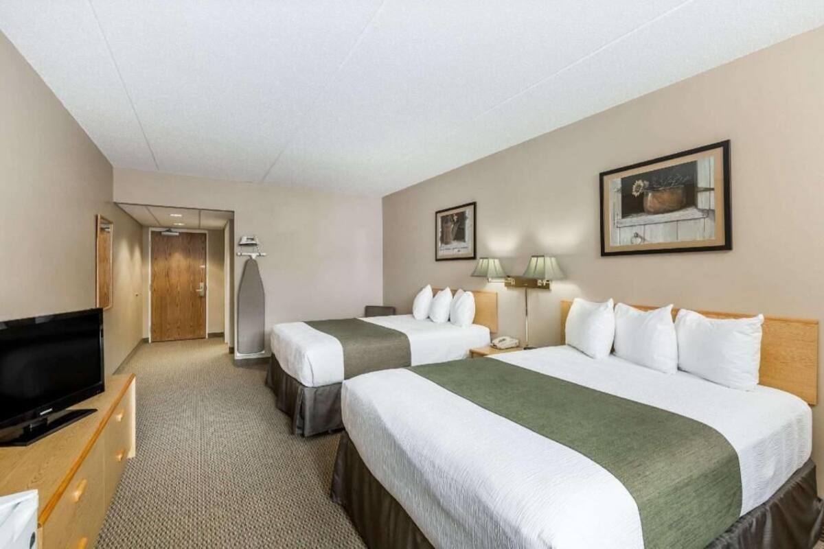 A hotel room with two beds, a television, a desk, and a door leading to a bathroom.