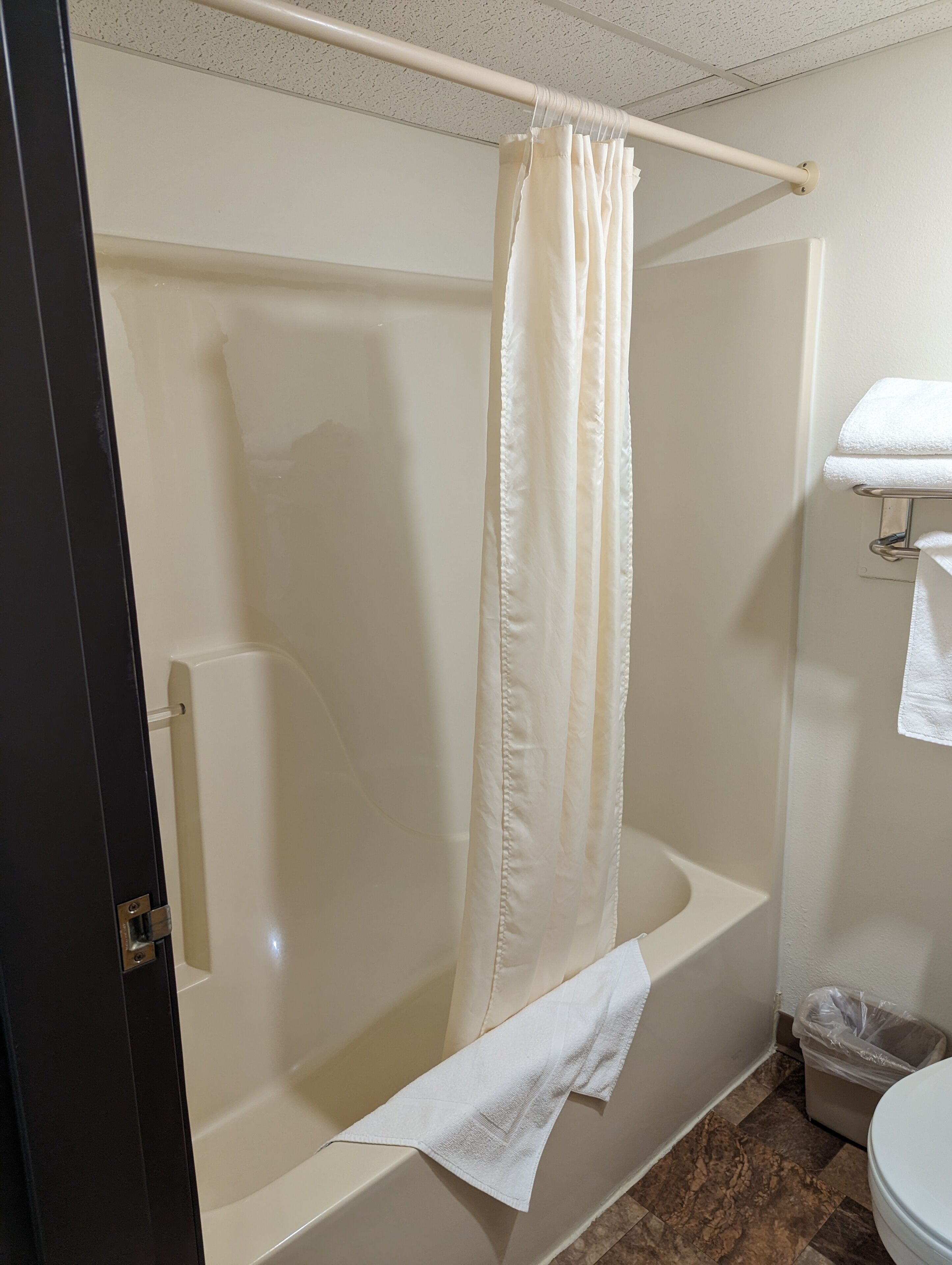 A bathroom with a bathtub, a shower curtain, a towel rack, and a toilet.