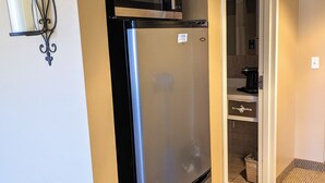 Una cocina compacta con un refrigerador de acero inoxidable, un microondas y una cafetera.