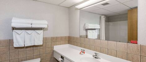 Un baño de hotel con lavamanos blanco, espejo y toallero.