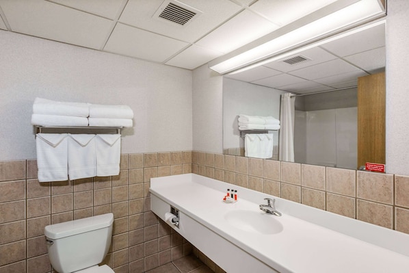 A hotel bathroom with a white sink, mirror, and towel rack.