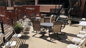 An outdoor patio area with tables and chairs, a sign reading "LIVELY FOED", and a staircase leading to an upper level.