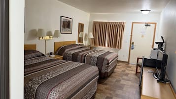 Habitación de hotel con dos camas, un escritorio con computadora, una caminadora y una ventana con cortinas.