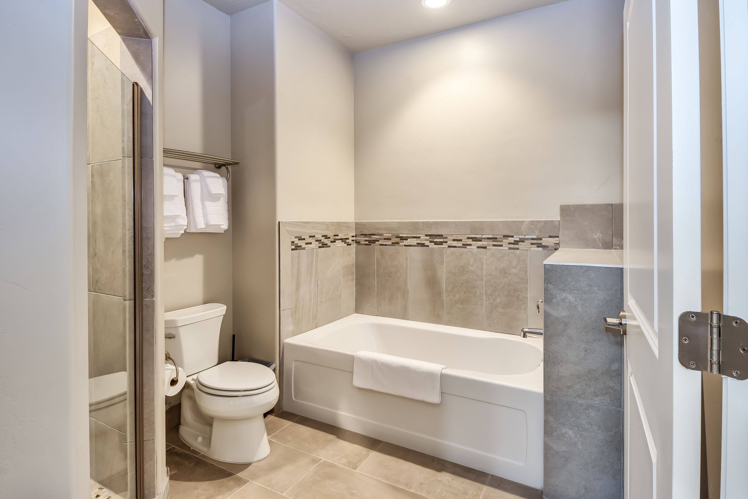 A modern bathroom with a toilet, bathtub, and shower area.