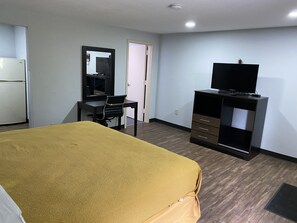 A hotel room with a bed, a desk with a chair, a television on a cabinet, and a door. - Hillside Motel (Glen Mills)