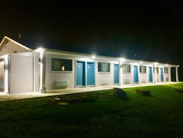 A row of single-story buildings with blue doors, likely a motel or B&B, with a well-lit exterior at night. - Hillside Motel (Glen Mills)