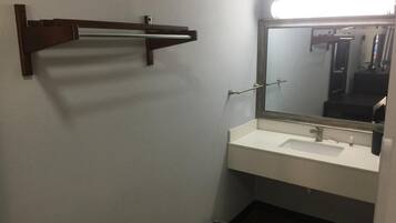 Un bagno con un lavandino bianco, uno specchio e un portasciugamani.