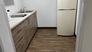 Una cocina compacta con un lavamanos, armarios de madera y un refrigerador blanco.