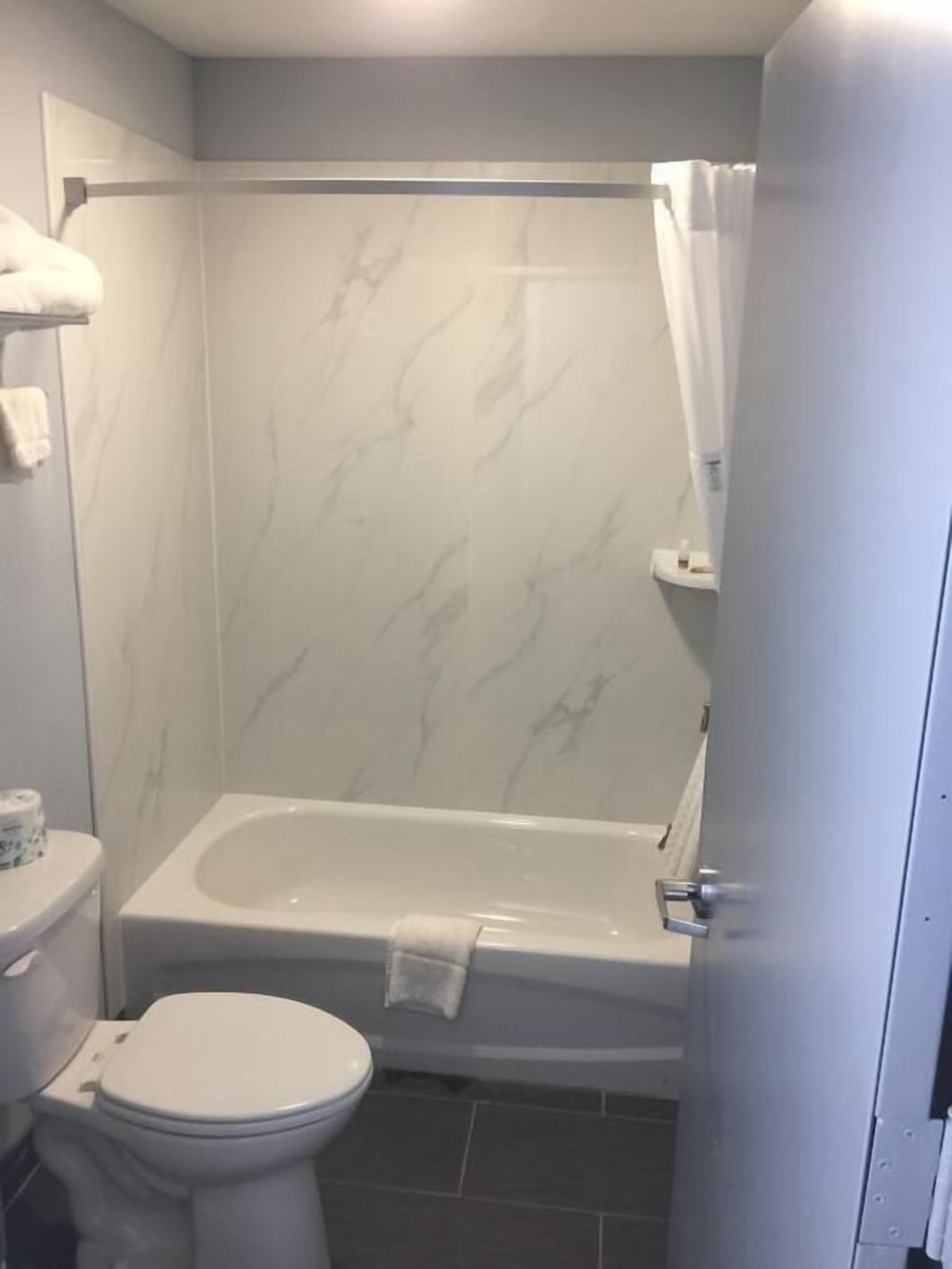 A bathroom with a white toilet, a white bathtub, and a shower curtain.