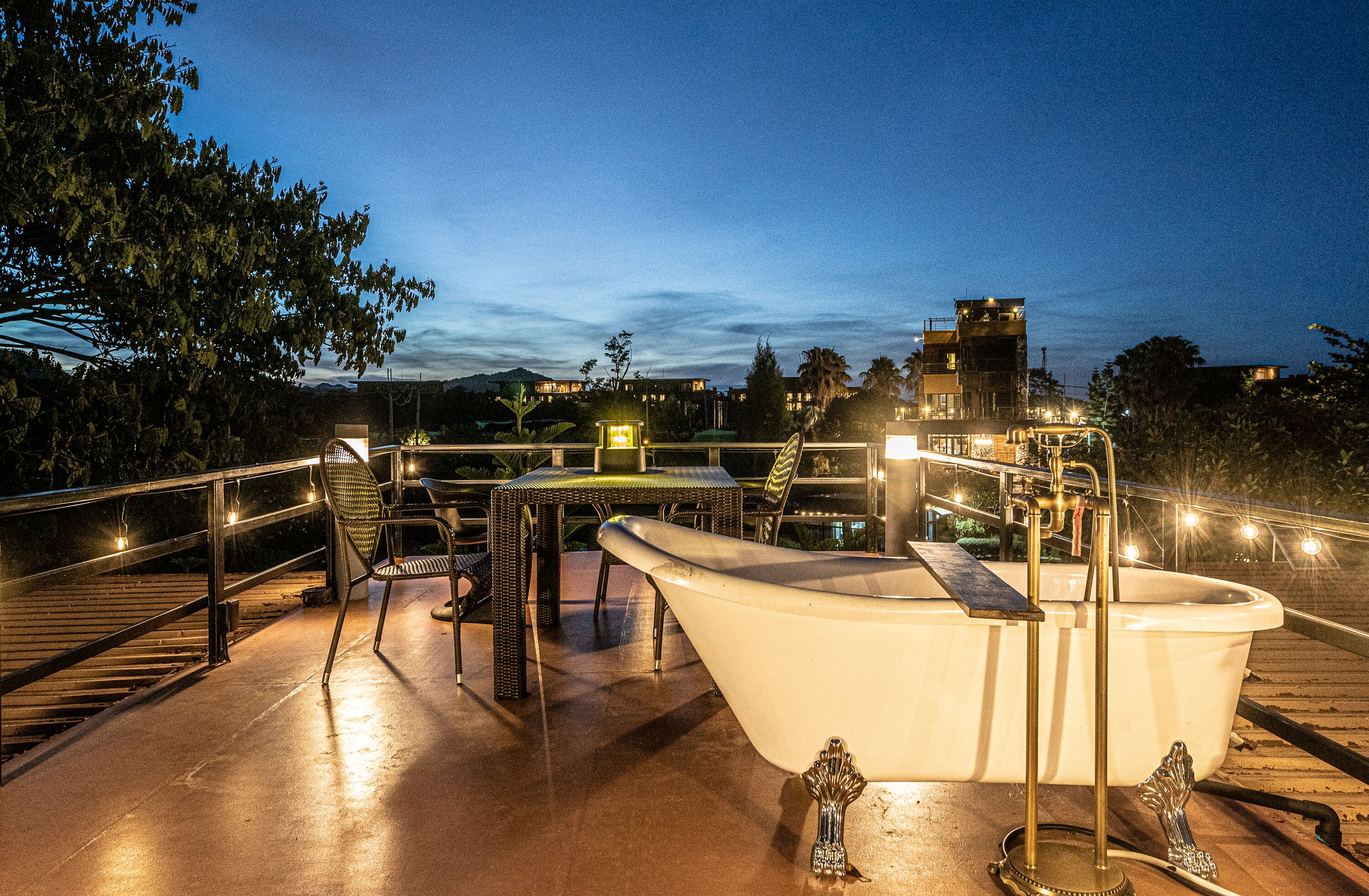 A rooftop pool area with a bathtub, lounge chairs, and a railing.
