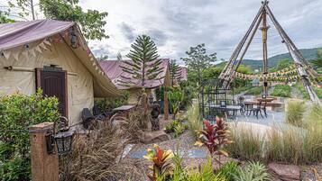 A rustic tented accommodation with a stone pathway leading to a seating area.